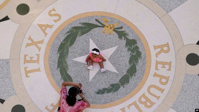 Michaela Herrera toma fotografías de su hija de ocho meses, Jayzaiyah, en el Capitolio de Texas el 6 de mayo de 2021. Más del 49% de los texanos menores de 18 años son hispanos, según estimaciones del censo reciente.
