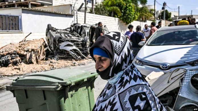 Los autos destruidos en un ataque con cohetes supuestamente disparados desde la Franja de Gaza se ven a través de una ventana dañada de una casa en la aldea de Arara, en el desierto de Negev, el 14 de octubre de 2023.