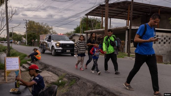 Una familia migrante de Venezuela pasa junto a un hombre comiendo en un puesto al borde de la carretera tras haber sido disuadida por las autoridades locales de cruzar el río Grande hacia Eagle Pass, en Texas, desde Piedras Negras, Coahuila, México el 7 de octubre. [REUTERS]