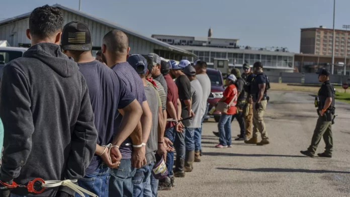Trabajadores esposados después de ser arrestados por agentes del Servicio de Inmigración y Control de Aduanas de Estados Unidos - Sputnik Mundo, 1920, 22.07.2025